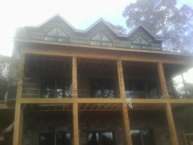 Dormers and porch framing on a large log home under construction — Roof Coating work by our crew in Pennsboro