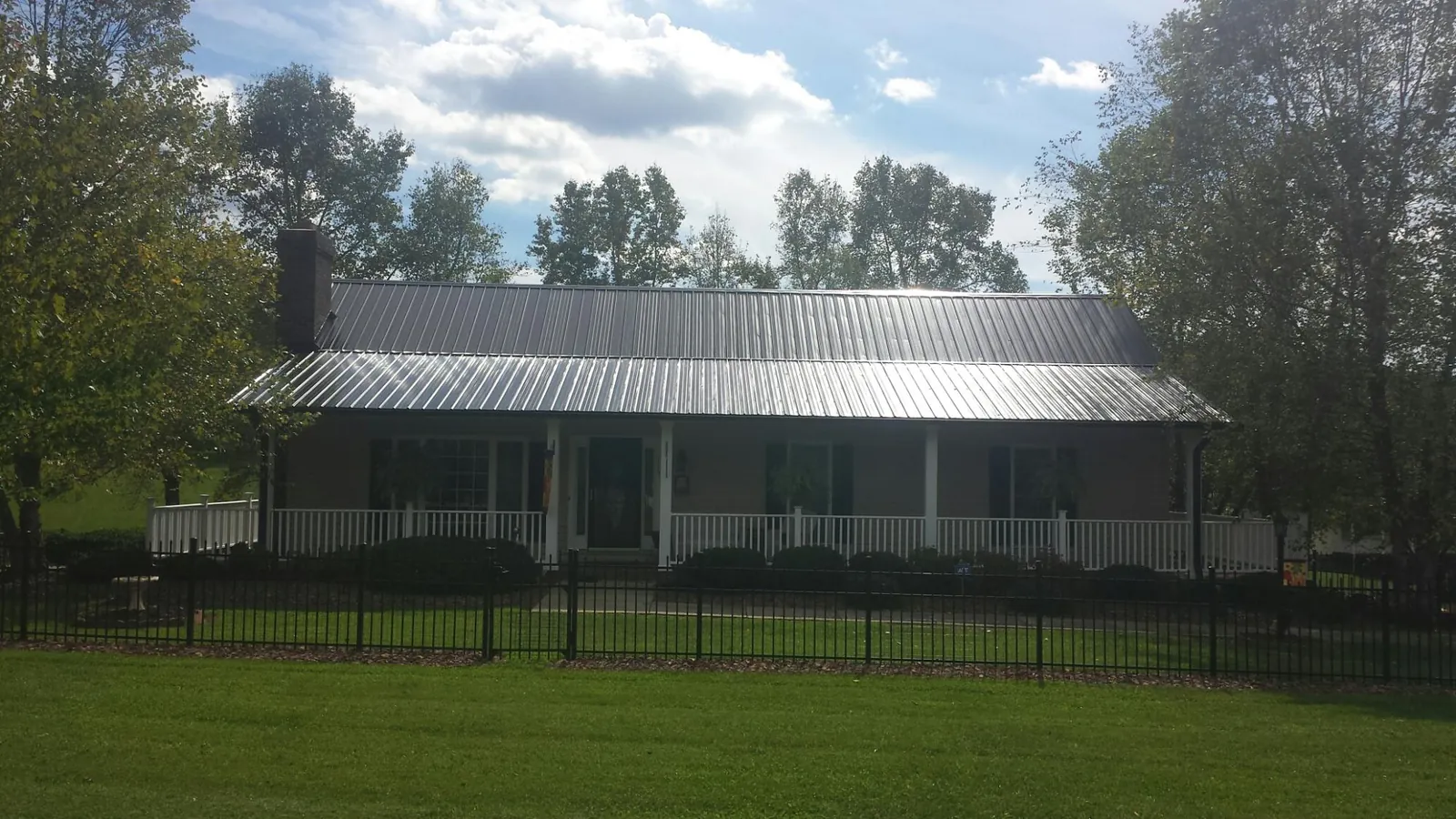Gray metal roof on a brick ranch with a full width front porch — Gutter Guard Installation work by our crew in Pennsboro