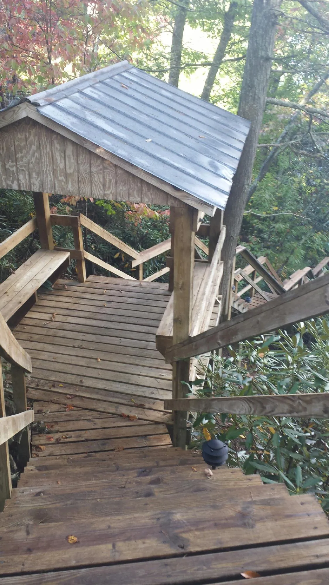 Metal roofed shelter over wooden steps on a wooded walkway — Skylight Repair & Installation work by our crew in Pennsboro