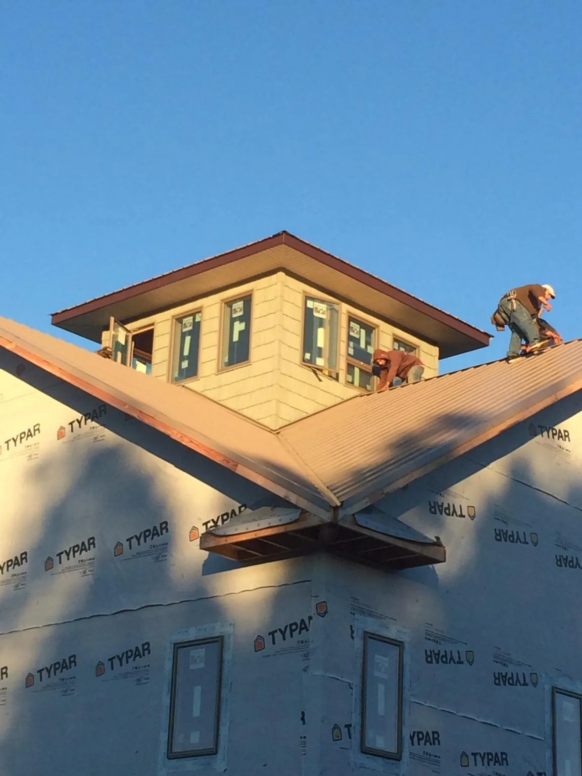 Roofers working around a rooftop cupola on a new metal roof at sunset — Roof Waterproofing in Pennsboro by Roofing Brothers